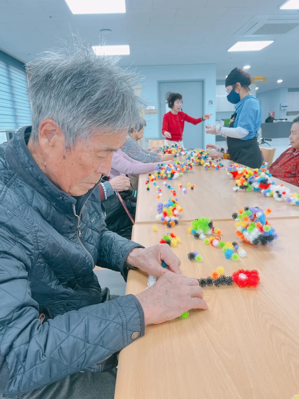 경기우리요양원 어르신이 색색의 만들기 교구로 손 활동에 집중하는 모습