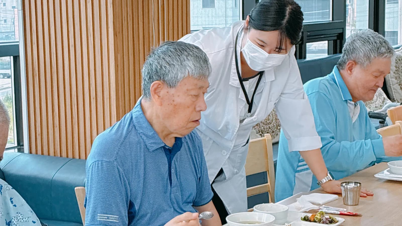 식당에서 직원이 식사 중인 어르신을 살피는 모습
